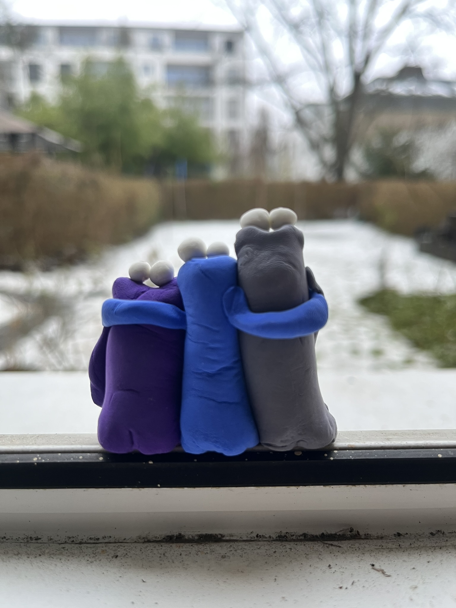 Drei Squigs Arm in Arm schauen aus dem Fenster auf Schnee
